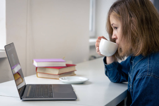 Adolescente s'assoit devant un ordinateur portable, apprentissage en ligne. - Photo, image
