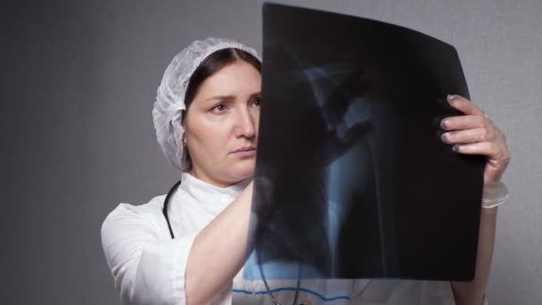 Mujer ortopedista mira la imagen de rayos X en la clínica - Metraje, vídeo