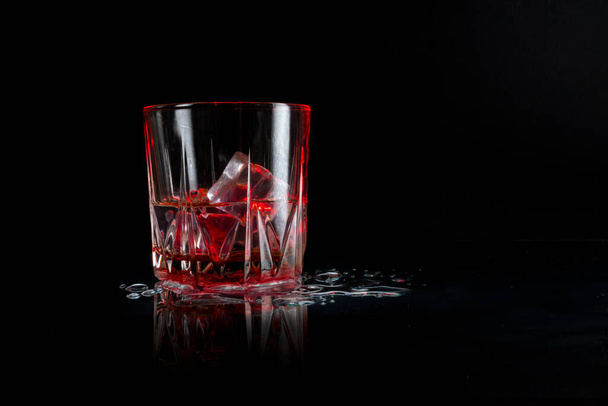 vidrio con hielo iluminado con luz roja - Foto, Imagen