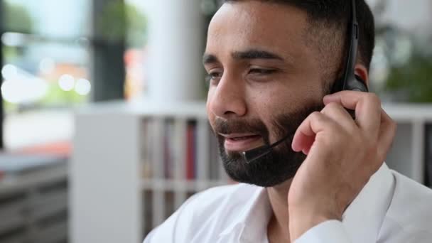 Close-up of successful Indian man, businessman, call center operator or consultant, headset, talking by online call, holds online business meeting, consultation, gives expert advice - Materiaali, video