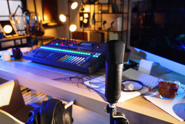 Microphone near table with professional mixing console in radio studio - Fotó, kép
