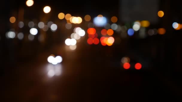 Bellissimo bokeh scintillante in sfondo scuro sfocato di notte. Il bokeh colorato rotondo brilla dalle luci dell'auto sulla strada della città. Sfocato con la sfocatura. Luci di città sfocate. Traffico bokeh. Riassunto - Filmati, video