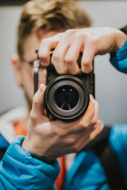 A vertical shot of a photographer holding a camera - Zdjęcie, obraz