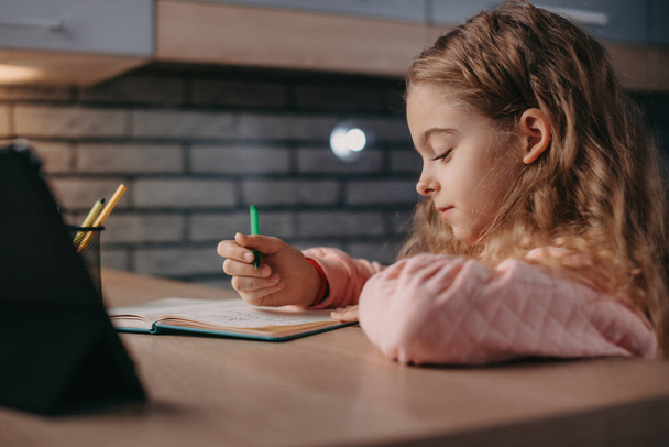 Gros plan portrait d'une fille apprenant l'anglais en ligne avec tablette. Isolement personnel. Coronavirus. Concept d'enseignement à domicile - Photo, image