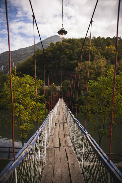 A beautiful view of a pier bridge lead to a wood green forest with a cloudy sky in Ovcar Banja, Serbia - Photo, Image