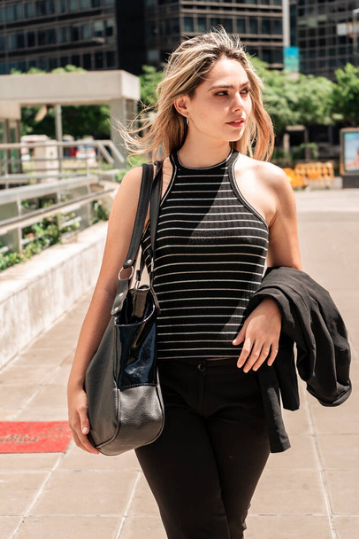 Portrait of a young business woman walking on a hot sunny day towards her office.Vertical orientation - Fotografie, Obrázek