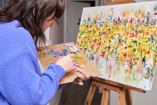 Молода жінка малює на полотні олійними фарбами вдома
. - Фото, зображення