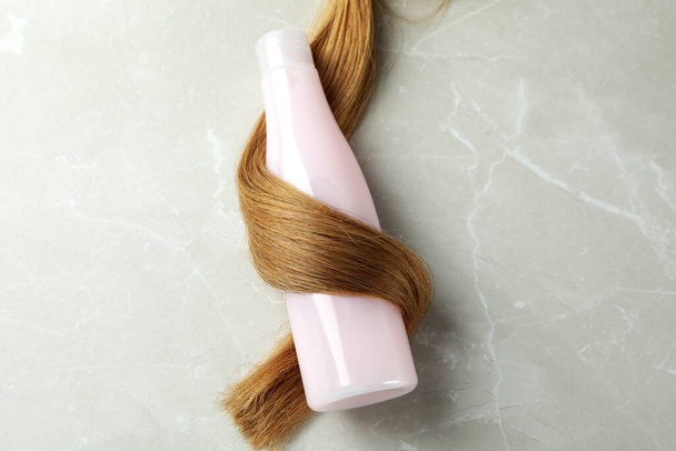 Μια τούφα από γυναικεία μαλλιά με σαμπουάν μπουκάλι - Φωτογραφία, εικόνα