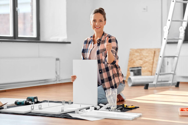 woman assembling furniture and showing thumbs up - Photo, image