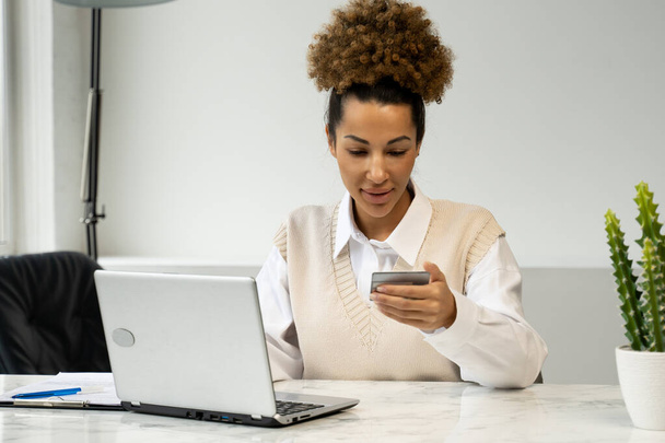African-American woman holding a credit card, sitting at a table with a laptop, shopping online, making Internet payments - Photo, image