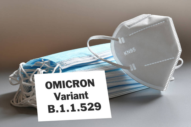 Covid-19 Omicron variant. Tekst "Omicron Variant" met veel beschermmaskers. Concept van bescherming tegen de nieuwe Omicron variant. - Foto, afbeelding