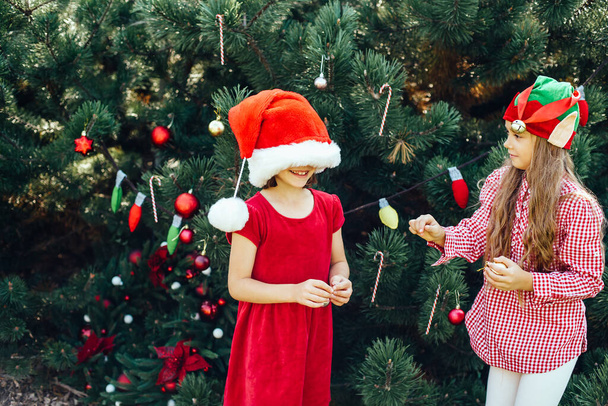 Frohe Weihnachten. Porträt von zwei fröhlichen lustigen Kindermädchen mit Weihnachtsmütze, die auf Weihnachten warten - Foto, Bild