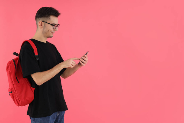 Houkutteleva mies opiskelija puhelimen pinkkiä taustaa vasten - Valokuva, kuva