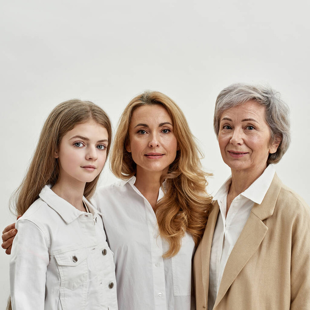 Three female generations hug and look at camera - Photo, Image