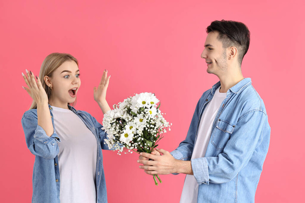 A guy gives a bouquet to a girl on pink background - Photo, Image