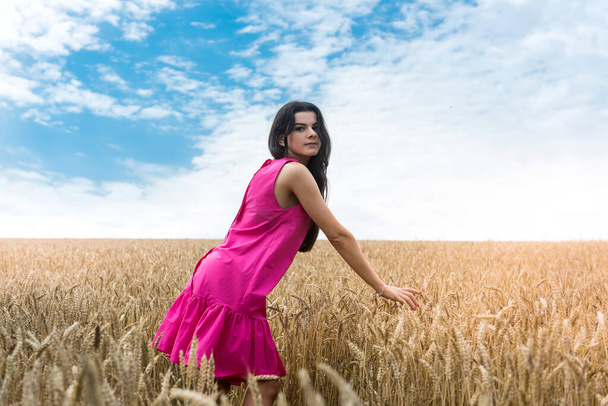 Sexy mujer delgada feliz camina en el verano en un campo de trigo. Señora disfrutando del pasatiempo en el campo - Foto, imagen