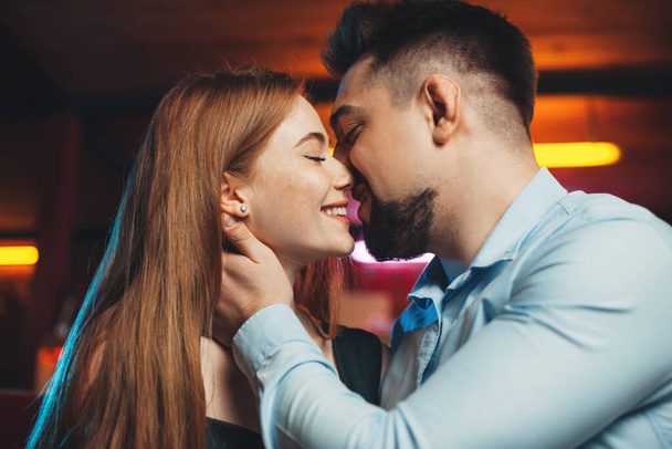 Vista lateral de cerca de un hombre besando a una mujer sentada en el restaurante. Día de San Valentín. Día de la familia. - Foto, imagen