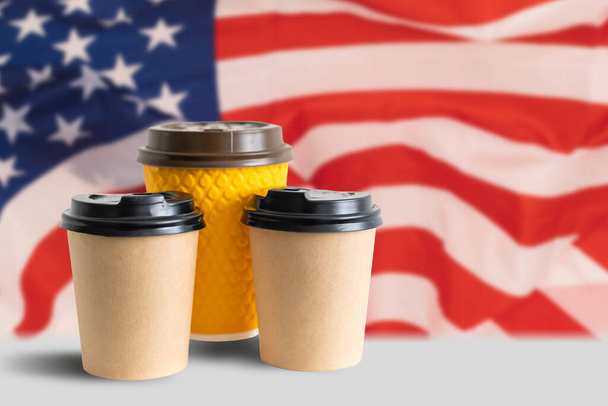 Zbliżenie amerykańskiej flagi z filiżanką papieru do kawy. Makieta filiżanki papieru do kawy - Zdjęcie, obraz
