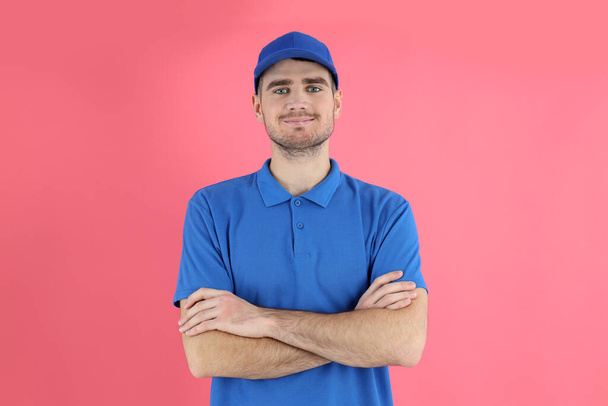 Entrega hombre en gorra y camiseta sobre fondo rosa - Foto, Imagen