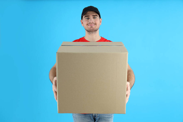 Delivery man holds box on blue background - Fotoğraf, Görsel