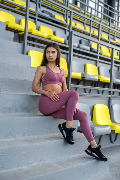 portrait attractive girl in sports wear posing at stadium before fitness exercise. Sport and recreation concept for health - Photo, Image