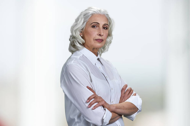 Mujer bastante mayor en blusa blanca clásica mirando a la cámara sobre fondo blanco. - Foto, Imagen