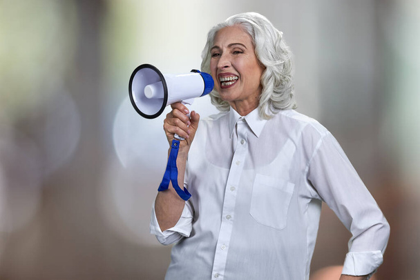 Експресивна старша жінка в білій блузці розмовляє в мегафон
. - Фото, зображення