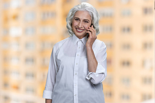 Heureuse femme d'affaires âgée parlant sur téléphone mobile. - Photo, image