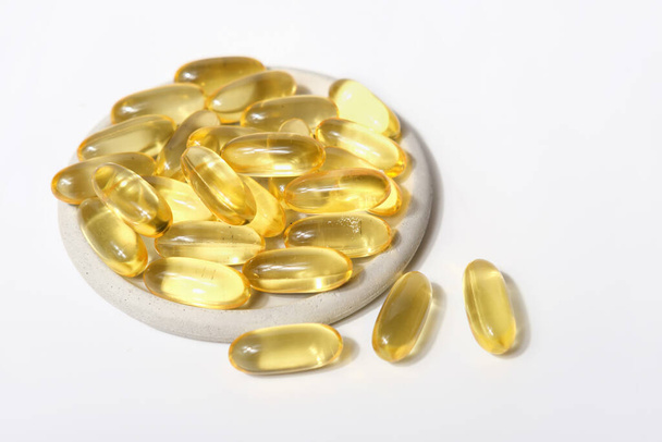 omega-3 capsules op een grijze plaat. visolie, kabeljauwlever voor vasculaire gezondheid en hartondersteuning. essentiële aanvulling voor gezond leven - Foto, afbeelding