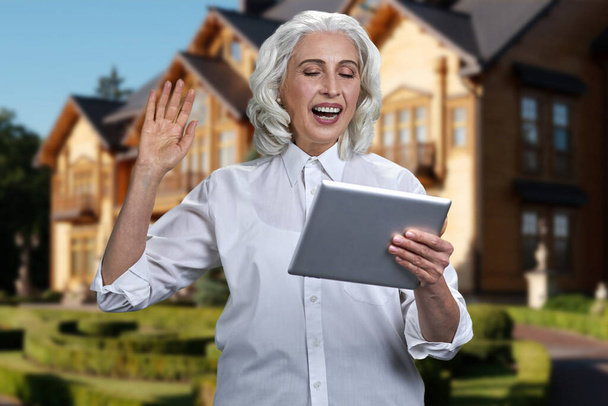 Excited senior woman waving with hand while looking at tablet pc. - Photo, Image