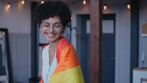 Black girl wears lgbt flag on her shoulders looking at the camera smiling - Filmagem, Vídeo