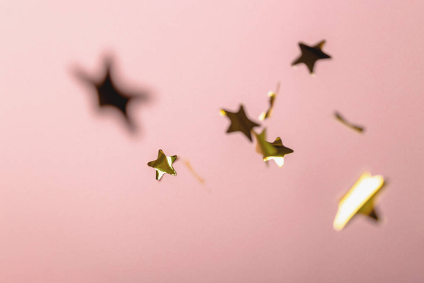 Фон з літаючими золотими зірками конфетті. Рожевий фон. Шпалери
. - Фото, зображення