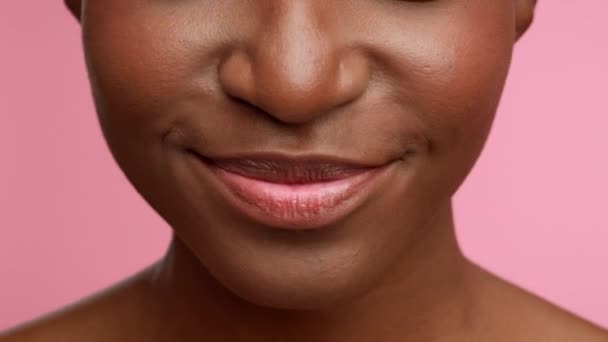 Afrikaanse vrouwen glimlachen met beugels breken tanden, roze achtergrond, close-up - Video