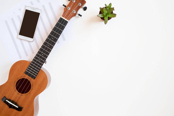 Workplace of a musician with a ukulele on a white background, top view, copy space. - Fotografie, Obrázek