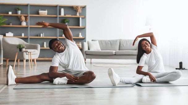 jovem casal preto fazendo lado dobrar esticar exercício juntos - Foto, Imagem