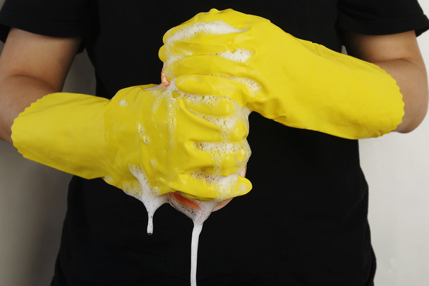 Рука в перчатках сжимает губку для чистки пеной
 - Фото, изображение