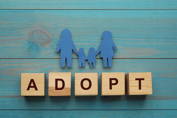 Familienfigur und Wort Adoption aus Würfeln auf hellblauem Holztisch - Foto, Bild