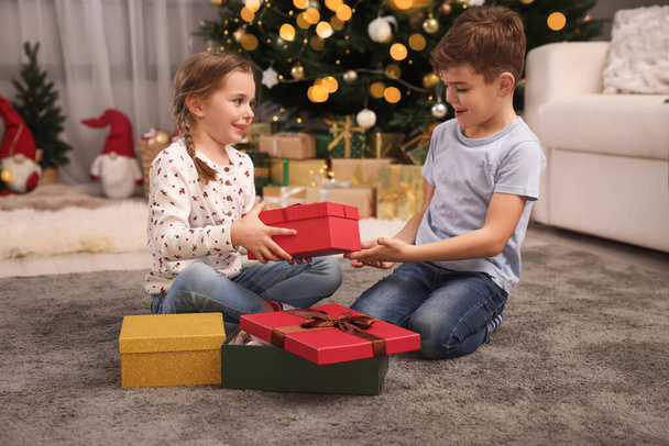 Cute little children with gift boxes near Christmas tree at home - Zdjęcie, obraz