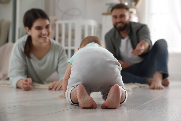 Happy parents watching their baby crawl on floor at home - Fotografie, Obrázek