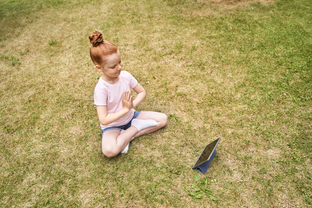 Pretty face. Red hair. Cute school child doing yoga exercise. Active vacation - Photo, image
