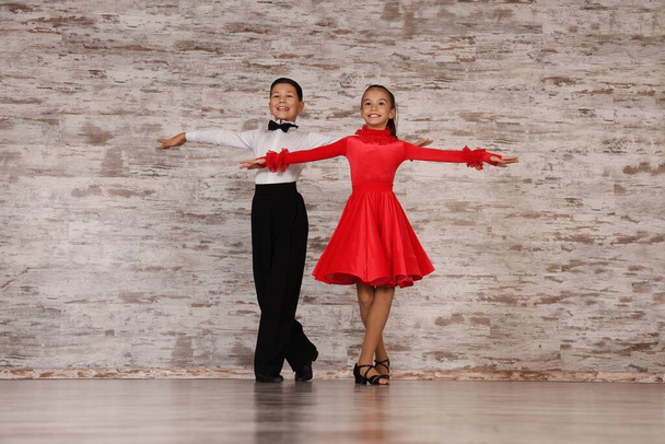 Beautifully dressed couple of kids dancing together in studio - Фото, изображение
