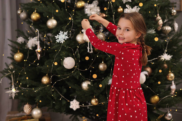 Cute little child decorating Christmas tree at home - Foto, imagen