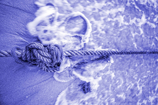 Ships rope knot on a tropical beach with tidal waves in PANTONE 17-3938 Very Peri colour - Foto, Bild