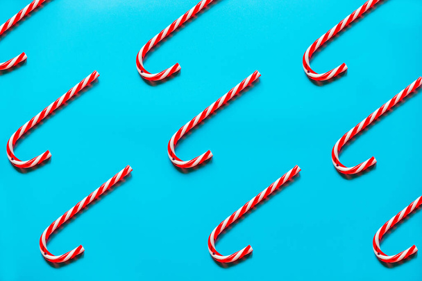 Bengalas de doces de Natal vermelho e branco na linha diagonal no fundo azul. Deitado plano e vista superior. - Foto, Imagem