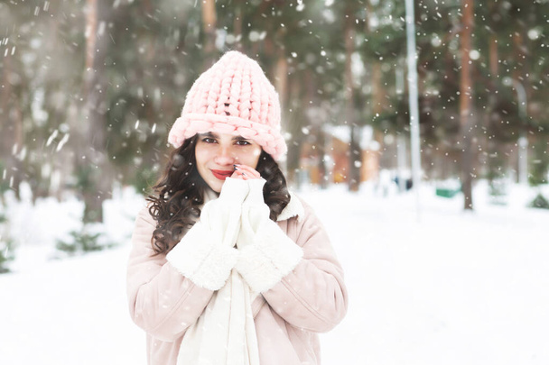 Příjemné kudrnaté brunetky žena nosí teplý kabát procházky v lese během sněžení. Prázdné místo - Fotografie, Obrázek