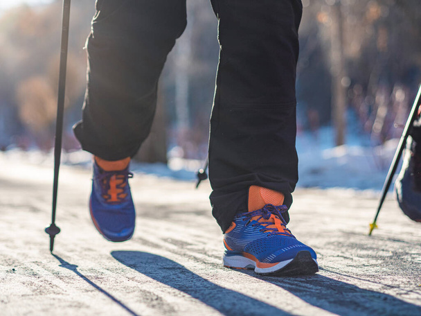 Primer plano piernas de un hombre, nórdico caminando en invierno. Recreación fitness y estilo de vida saludable al aire libre en la naturaleza. Motivación y paisaje invernal inspirador. - Foto, Imagen