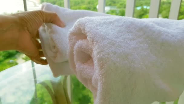 4k video, zbliżenie ręki kobiety dotykającej miękkiego białego ręcznika frotte na balkonie, na tle morza i parku - Materiał filmowy, wideo