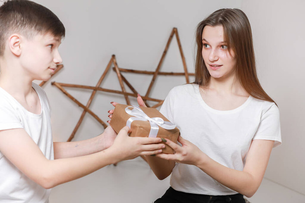 Mladý muž dal dívce dárkovou krabici. vánoční a novoroční koncept. mladý přítel dává překvapení v krabici s bílou stuhou na jeho přítelkyni. - Fotografie, Obrázek