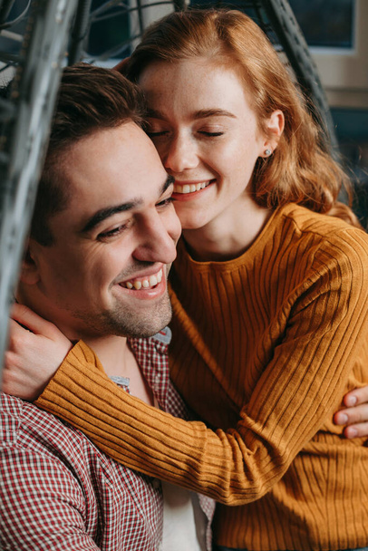 Close-up portrait of a couple sitting on a couch embracing each other and smiling. Living room interior. Happy face. Love - Photo, Image