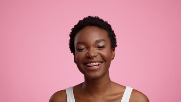 Щаслива афроамериканська леді посміхається позує на рожевому тлі
 - Кадри, відео